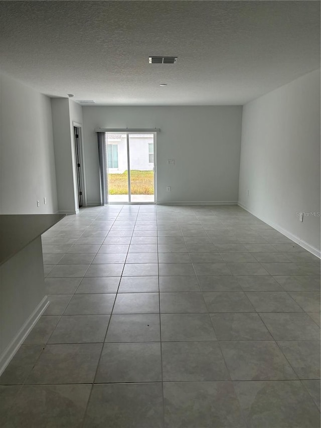 unfurnished room featuring a textured ceiling and light tile patterned flooring