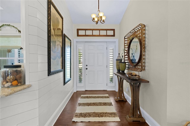 foyer entrance featuring lofted ceiling, a notable chandelier, and dark hardwood / wood-style floors