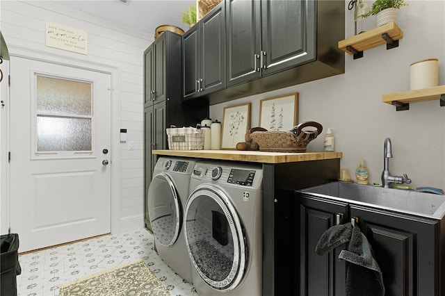 clothes washing area with separate washer and dryer, wood walls, cabinets, and sink