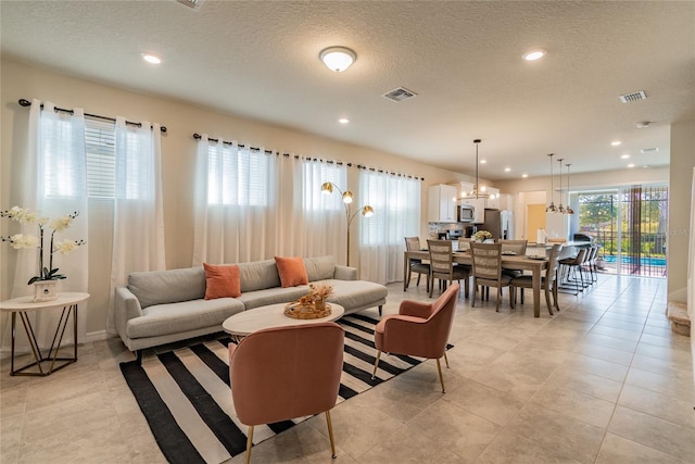 tiled living room featuring a textured ceiling and a healthy amount of sunlight