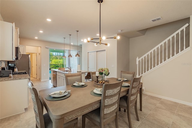 dining area featuring light tile patterned flooring, a chandelier, and sink