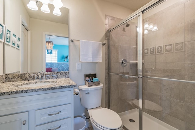 bathroom with an enclosed shower, vanity, toilet, and an inviting chandelier