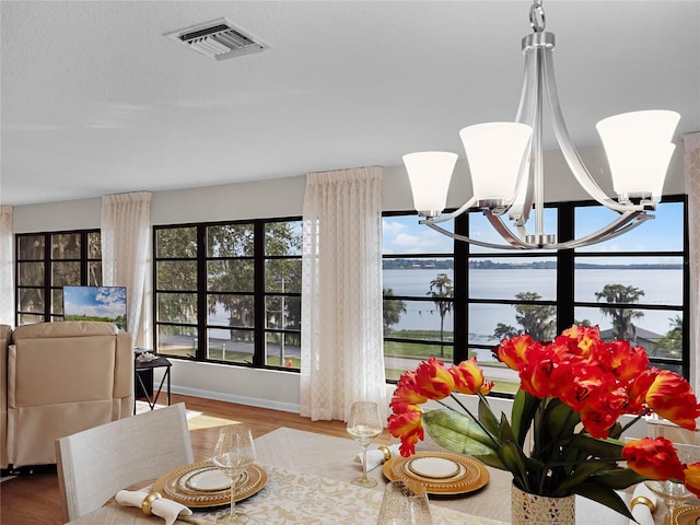 dining room featuring a water view, hardwood / wood-style flooring, and an inviting chandelier