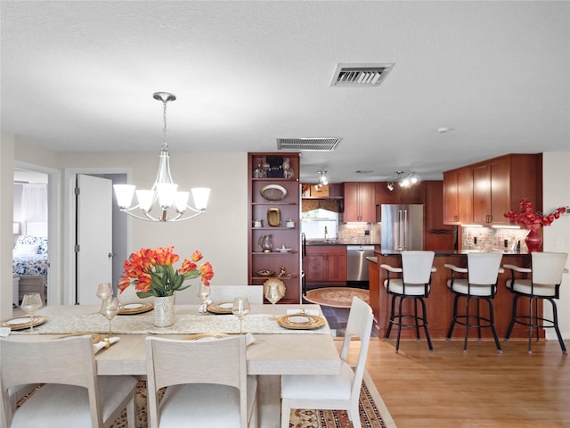 dining space with an inviting chandelier and light wood-type flooring