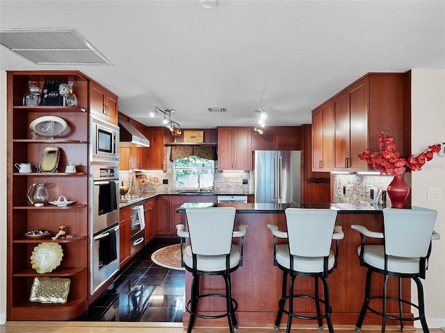 kitchen with ventilation hood, decorative backsplash, a kitchen breakfast bar, and stainless steel appliances