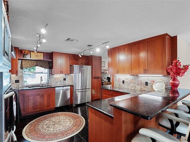 kitchen with kitchen peninsula, stainless steel appliances, decorative backsplash, and dark tile patterned floors