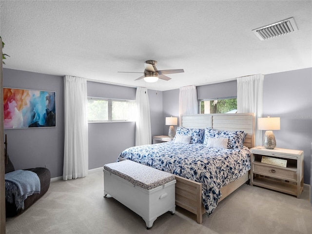 carpeted bedroom featuring multiple windows, a textured ceiling, and ceiling fan