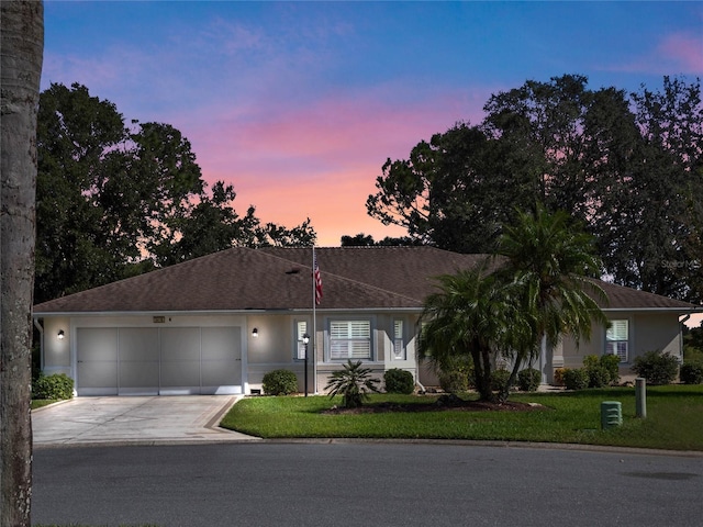 ranch-style house featuring a garage and a lawn