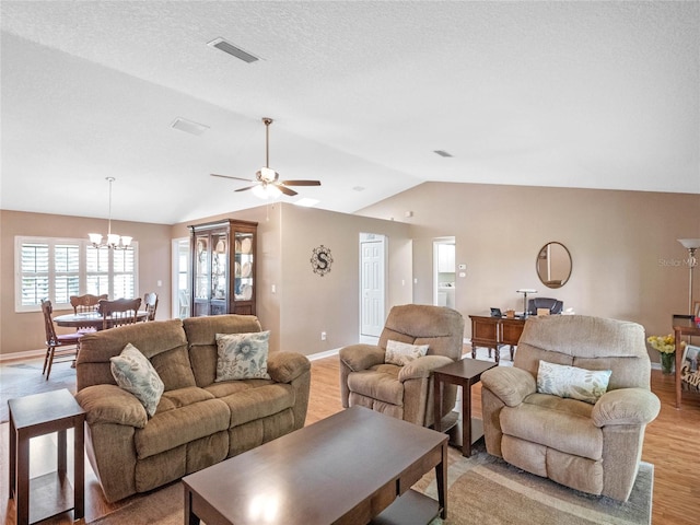 living room featuring a textured ceiling, vaulted ceiling, light hardwood / wood-style floors, and ceiling fan with notable chandelier