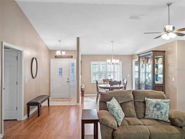 living room with ceiling fan with notable chandelier, a textured ceiling, light wood-type flooring, and lofted ceiling