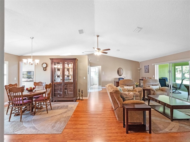 living room with light hardwood / wood-style floors, ceiling fan with notable chandelier, a textured ceiling, and vaulted ceiling