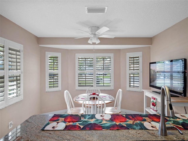 dining area with ceiling fan and a textured ceiling