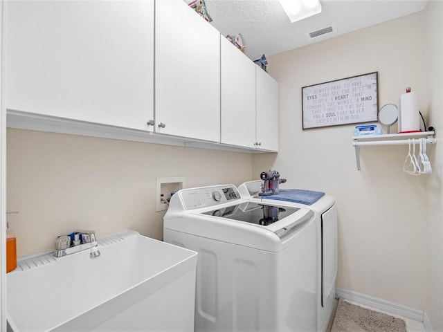 laundry room featuring cabinets, a textured ceiling, sink, and washer and dryer