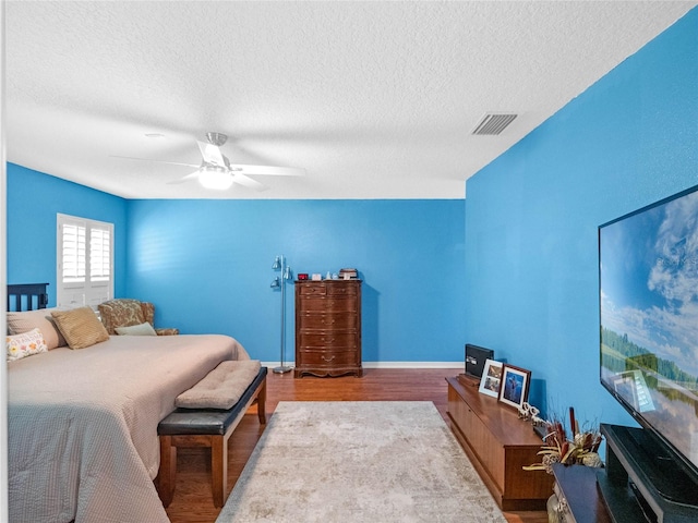 bedroom with hardwood / wood-style floors, ceiling fan, and a textured ceiling