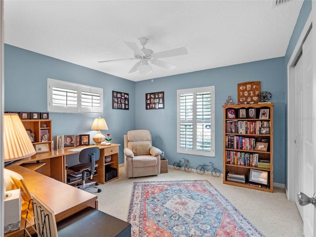 carpeted office space featuring ceiling fan