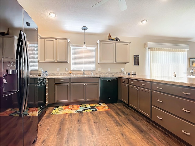 kitchen featuring sink, dark wood-type flooring, hanging light fixtures, kitchen peninsula, and black appliances