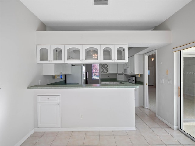 kitchen featuring kitchen peninsula, white cabinetry, light tile patterned flooring, and white appliances