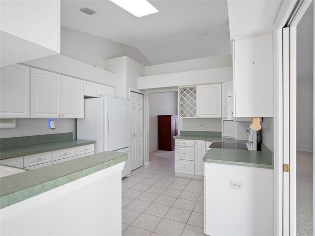 kitchen with lofted ceiling, white cabinets, white refrigerator, light tile patterned flooring, and range