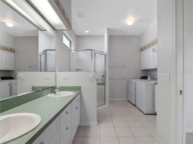 bathroom featuring vanity, a textured ceiling, washing machine and clothes dryer, tile patterned flooring, and a shower with shower door