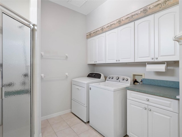 washroom featuring washing machine and dryer, light tile patterned flooring, and cabinets