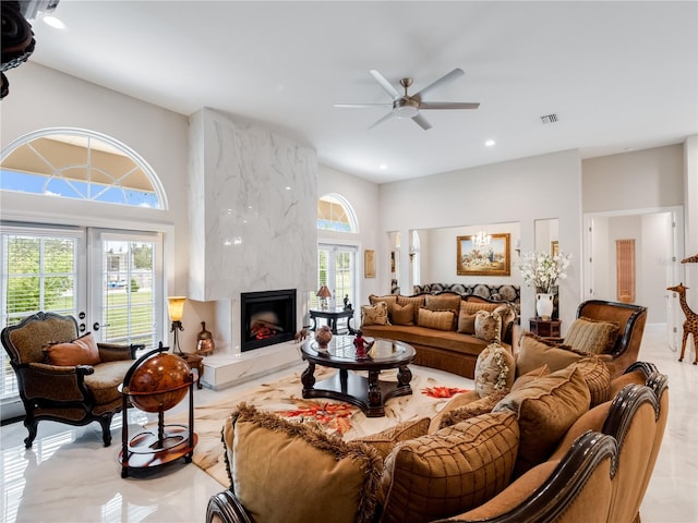 living room with a fireplace, a high ceiling, ceiling fan, and a healthy amount of sunlight