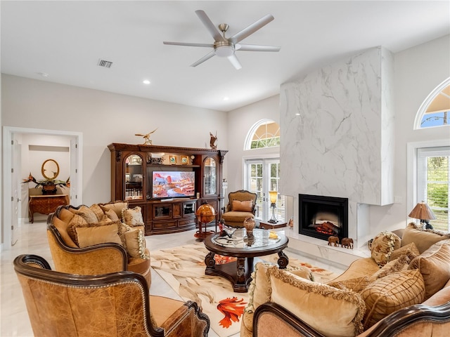 tiled living room with a fireplace, ceiling fan, and plenty of natural light