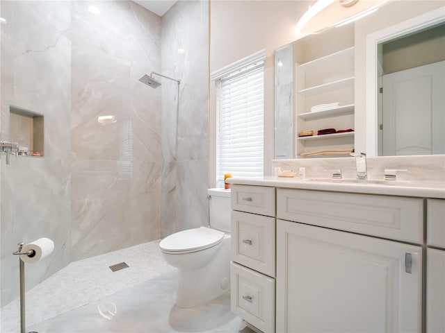 bathroom with vanity, toilet, and a tile shower