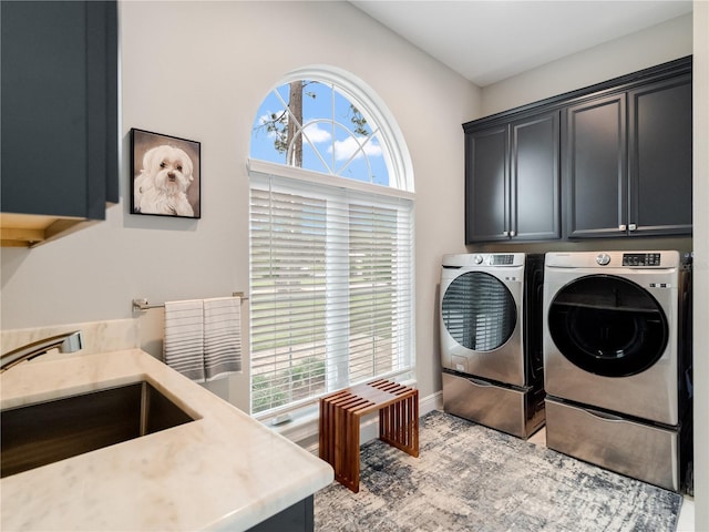 clothes washing area with cabinets, washer and clothes dryer, and sink