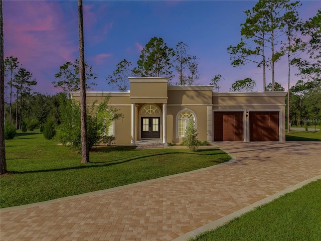 view of front of house with french doors, a garage, and a lawn