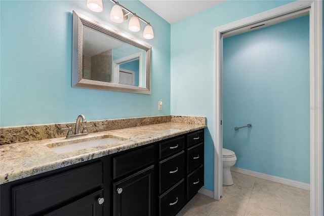 bathroom with baseboards, vanity, and toilet