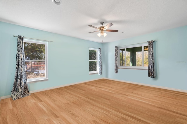 spare room with ceiling fan, light wood-style flooring, baseboards, and a textured ceiling