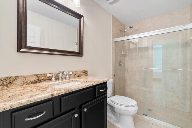 bathroom featuring toilet, a stall shower, tile patterned flooring, and vanity