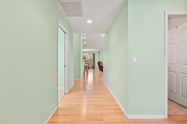 corridor with light wood-style floors, recessed lighting, visible vents, and baseboards