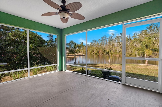 unfurnished sunroom with a ceiling fan, a wealth of natural light, and a water view