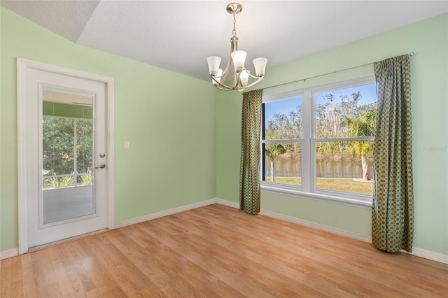 unfurnished dining area featuring a notable chandelier, wood finished floors, and baseboards