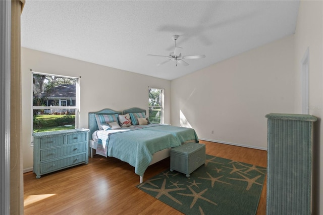 bedroom with ceiling fan, wood-type flooring, and a textured ceiling