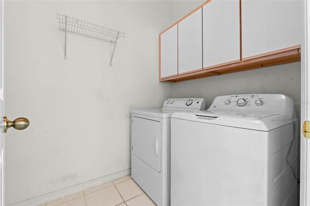 laundry area featuring washer and dryer, cabinets, and light tile patterned floors