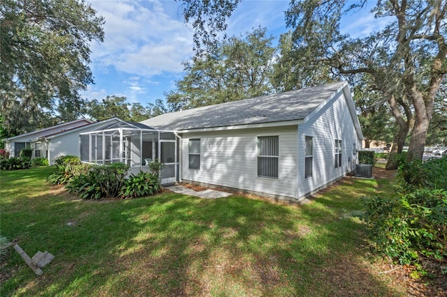 rear view of property with central AC unit, a lanai, and a yard