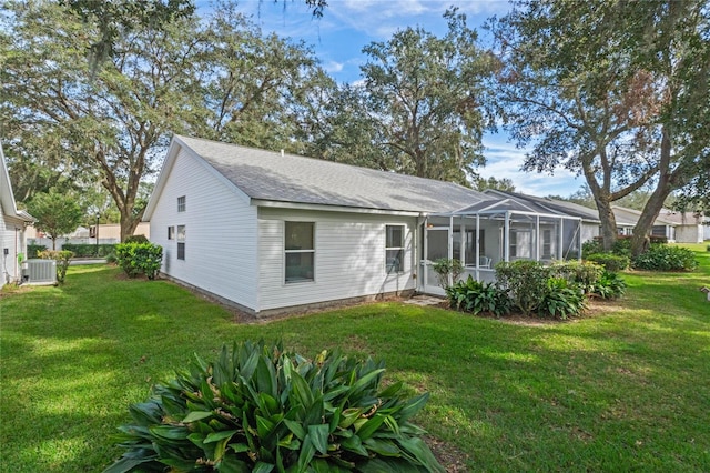 back of property featuring a lanai, a lawn, and central AC unit