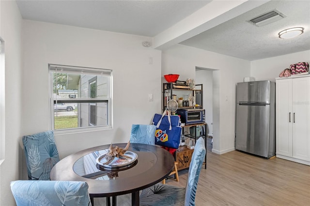 dining area with light hardwood / wood-style flooring and a textured ceiling