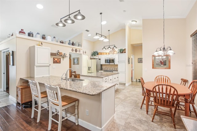 kitchen featuring a kitchen bar, decorative light fixtures, fridge with ice dispenser, and white cabinets