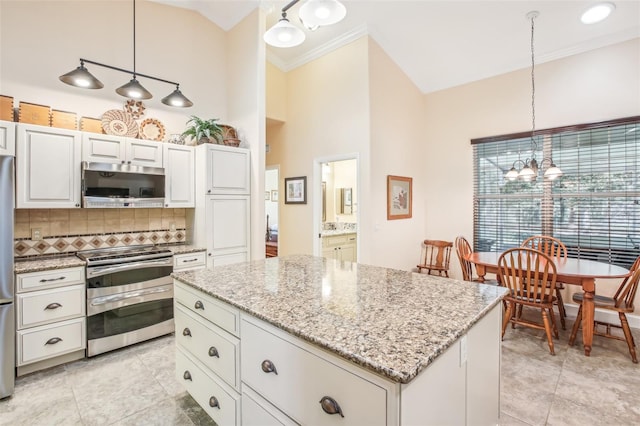 kitchen featuring backsplash, decorative light fixtures, a kitchen island, and appliances with stainless steel finishes