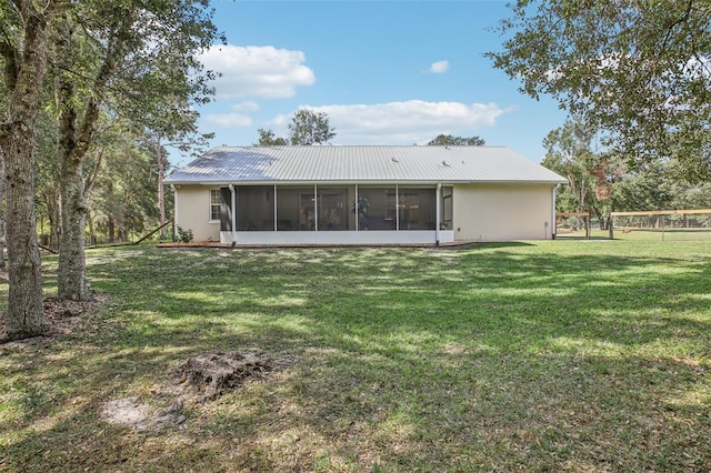 rear view of property with a lawn and a sunroom