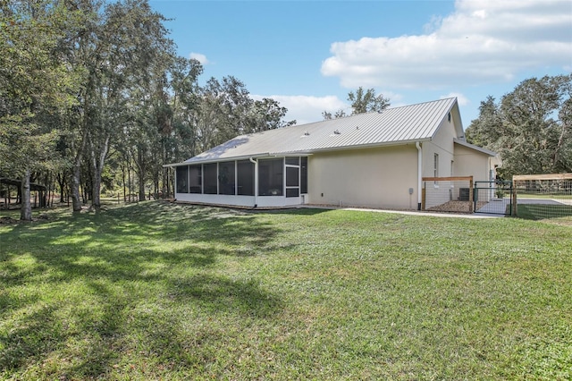 back of house featuring a sunroom and a lawn