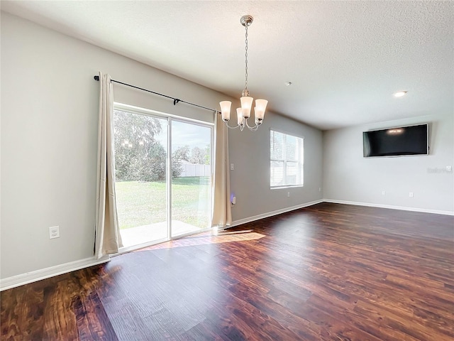 interior space with a textured ceiling, dark hardwood / wood-style flooring, and a notable chandelier