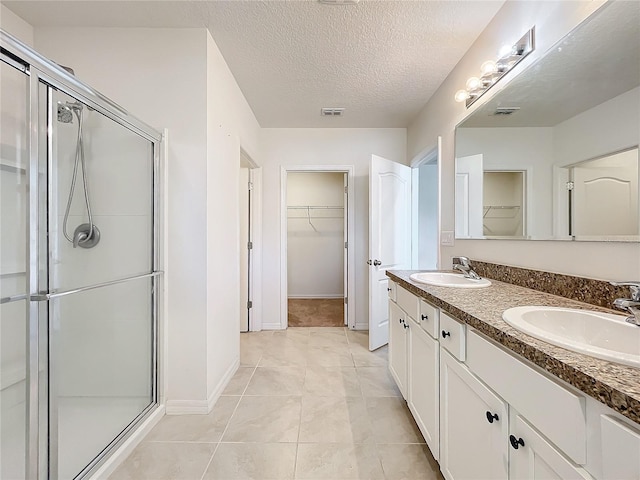 bathroom with vanity, a textured ceiling, tile patterned floors, and an enclosed shower