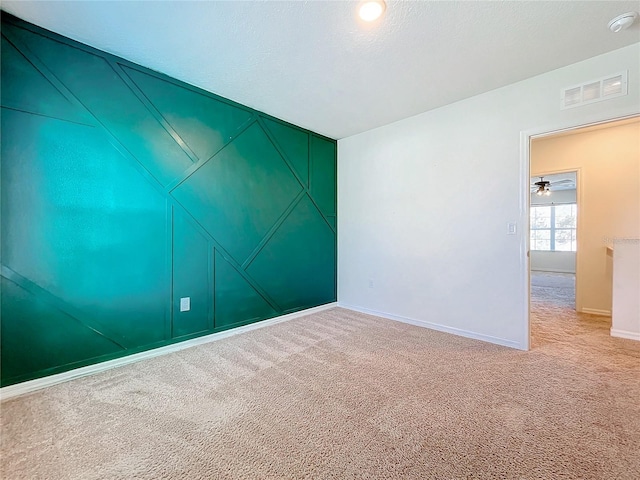 carpeted spare room featuring ceiling fan and a textured ceiling