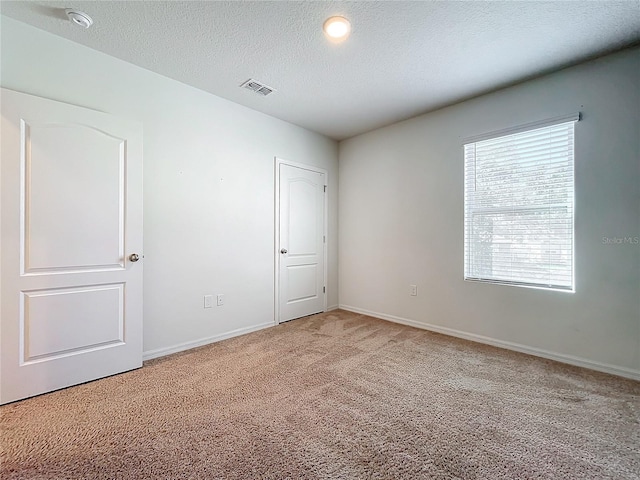 carpeted spare room with a textured ceiling