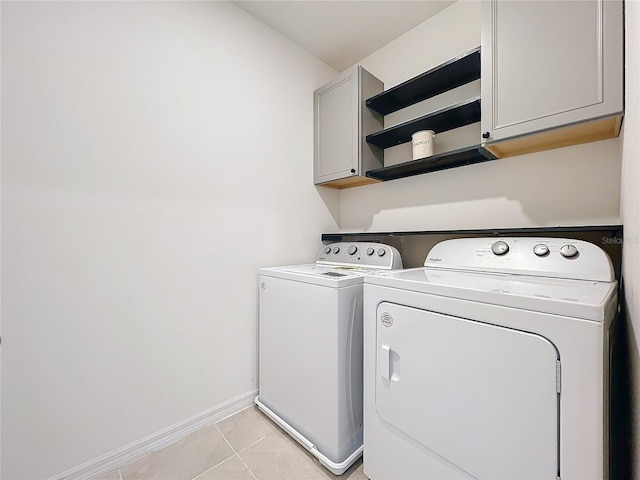 laundry area featuring cabinets, light tile patterned floors, and washer and dryer