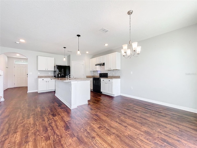 kitchen featuring dark hardwood / wood-style flooring, an island with sink, pendant lighting, white cabinets, and black appliances